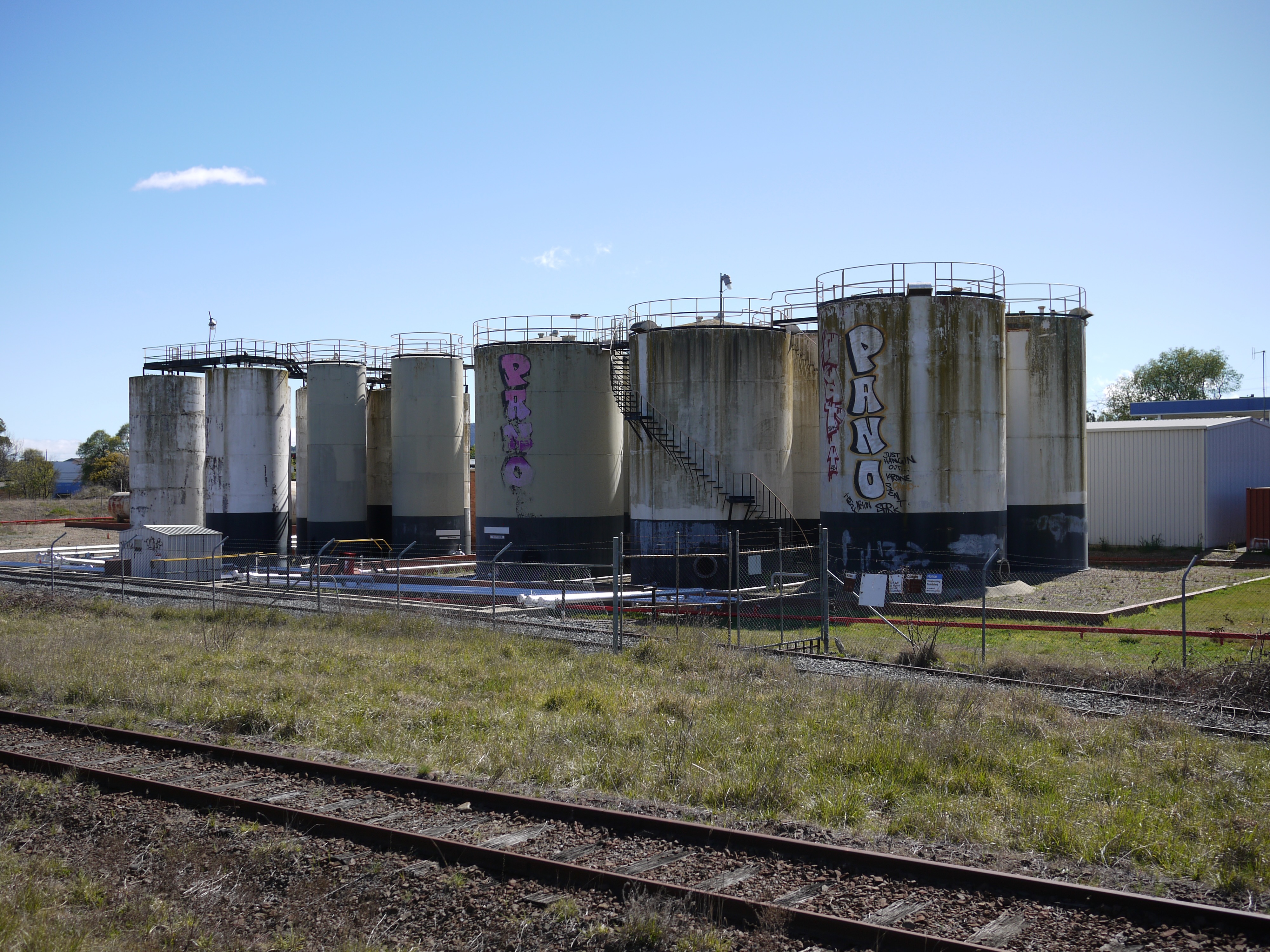Some sort of industial storage, covered in graffit, seen from the train